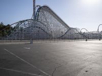 a roller coaster coaster on a track next to an empty parking lot in an amusement area