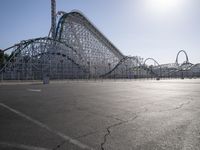 a roller coaster coaster on a track next to an empty parking lot in an amusement area