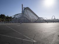 a roller coaster coaster on a track next to an empty parking lot in an amusement area