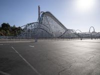 a roller coaster coaster on a track next to an empty parking lot in an amusement area