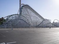 a roller coaster coaster on a track next to an empty parking lot in an amusement area