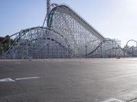 a roller coaster coaster on a track next to an empty parking lot in an amusement area