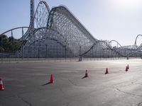 a roller coaster coaster on a track next to an empty parking lot in an amusement area