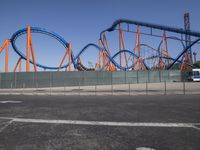 a roller coaster on display in a parking lot with an empty lot and the roller coaster behind it