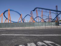 a roller coaster on display in a parking lot with an empty lot and the roller coaster behind it