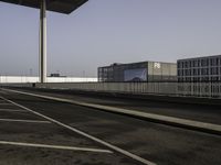 a very wide empty parking lot near some buildings and a street light on the top