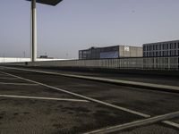 a very wide empty parking lot near some buildings and a street light on the top