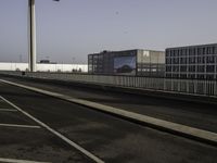 a very wide empty parking lot near some buildings and a street light on the top