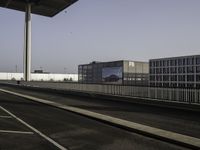 a very wide empty parking lot near some buildings and a street light on the top