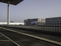 a very wide empty parking lot near some buildings and a street light on the top