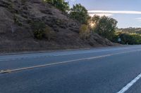 a motorcycle parked on the side of the road near a hillside with a sign in the distance