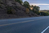 a motorcycle parked on the side of the road near a hillside with a sign in the distance