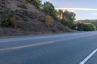 a motorcycle parked on the side of the road near a hillside with a sign in the distance