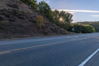 a motorcycle parked on the side of the road near a hillside with a sign in the distance