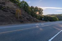 a motorcycle parked on the side of the road near a hillside with a sign in the distance