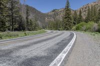 the car is travelling down the empty country road in the mountains on the way to a mountain pass