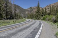 the car is travelling down the empty country road in the mountains on the way to a mountain pass