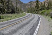 the car is travelling down the empty country road in the mountains on the way to a mountain pass