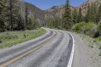 the car is travelling down the empty country road in the mountains on the way to a mountain pass