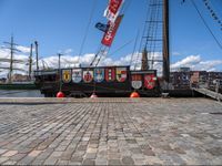 the ship has banners on it near a dock with boats in the water and buildings