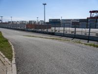 a parking lot with grass on one side and buildings on the other side, in front of the road and in the background