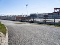 a parking lot with grass on one side and buildings on the other side, in front of the road and in the background