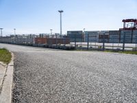 a parking lot with grass on one side and buildings on the other side, in front of the road and in the background