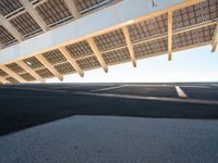 a parking lot filled with lots of empty asphalt under a roof near a beach with lots of sun shining through the roof