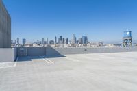 rooftop parking space with city buildings in the distance with a water tower in the middle of the photo