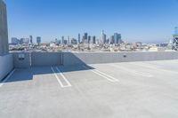 rooftop parking space with city buildings in the distance with a water tower in the middle of the photo