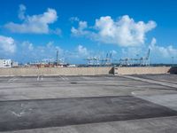 an empty parking lot with large boats out side and blue sky in background near it