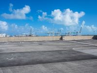 an empty parking lot with large boats out side and blue sky in background near it