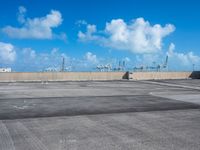 an empty parking lot with large boats out side and blue sky in background near it