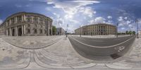 360 view in front of a round building with blue sky and clouds above it and with two bicycles parked in the foreground