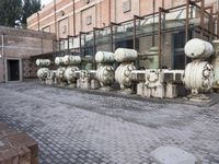 a row of fire hydrants lined up outside a building with a lot of pipes