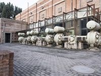 a row of fire hydrants lined up outside a building with a lot of pipes