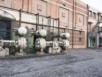 a row of fire hydrants lined up outside a building with a lot of pipes