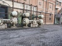 a row of fire hydrants lined up outside a building with a lot of pipes