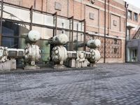 a row of fire hydrants lined up outside a building with a lot of pipes