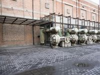 a row of fire hydrants lined up outside a building with a lot of pipes