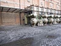 a row of fire hydrants lined up outside a building with a lot of pipes