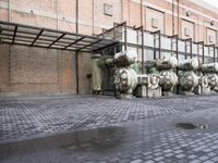 a row of fire hydrants lined up outside a building with a lot of pipes