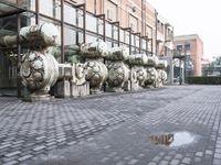 a row of fire hydrants lined up outside a building with a lot of pipes