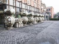 a row of fire hydrants lined up outside a building with a lot of pipes