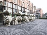 a row of fire hydrants lined up outside a building with a lot of pipes