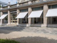 a row of windows that are covered with awnings on a sidewalk in front of a building