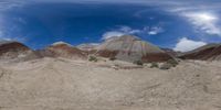 the barren terrain in the foreground shows the sky and clouds are white with blue hues