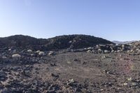 a pile of rocks in the middle of a barren area with many small rocks around