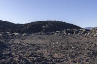 a pile of rocks in the middle of a barren area with many small rocks around