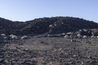 a pile of rocks in the middle of a barren area with many small rocks around